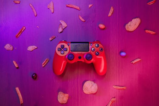 Stylish red game controller surrounded by snacks on a vibrant purple background.