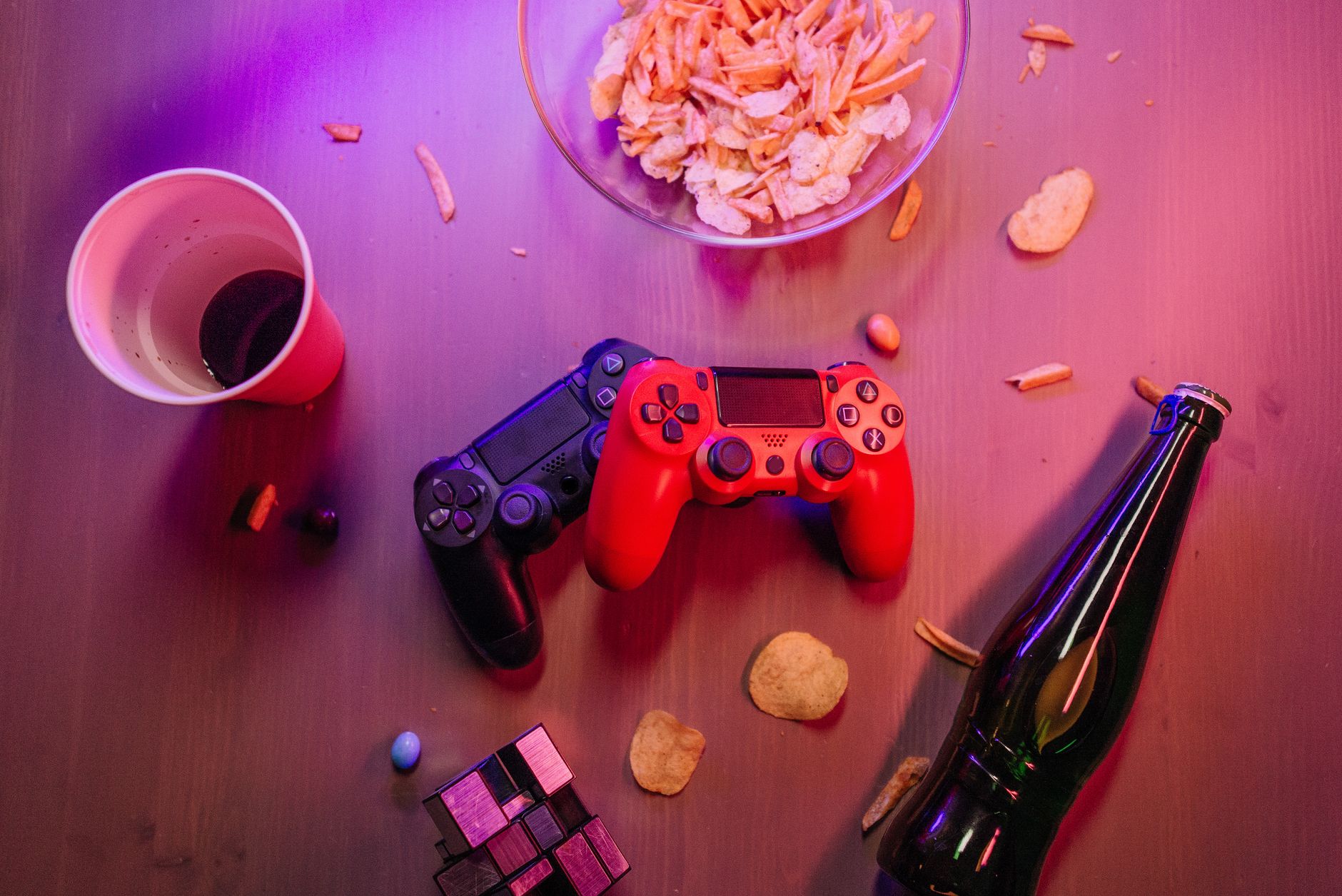 Top view of a gaming setup with controllers, snacks, and drinks, perfect for a cozy game night.