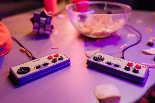 Retro gaming scene featuring classic 8-bit controllers and a relaxed setting with snacks.