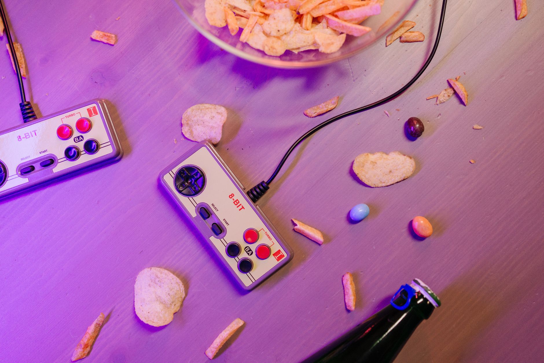 Vintage game controllers and snacks on a table create a nostalgic gaming vibe.