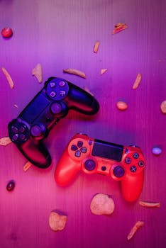 Two gaming controllers surrounded by snacks on a table with a vibrant purple hue.
