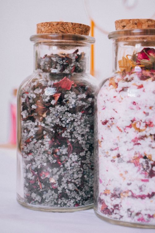 Free Close-up of decorative bath salts in glass jars with cork lids, adorned with dried petals. Stock Photo