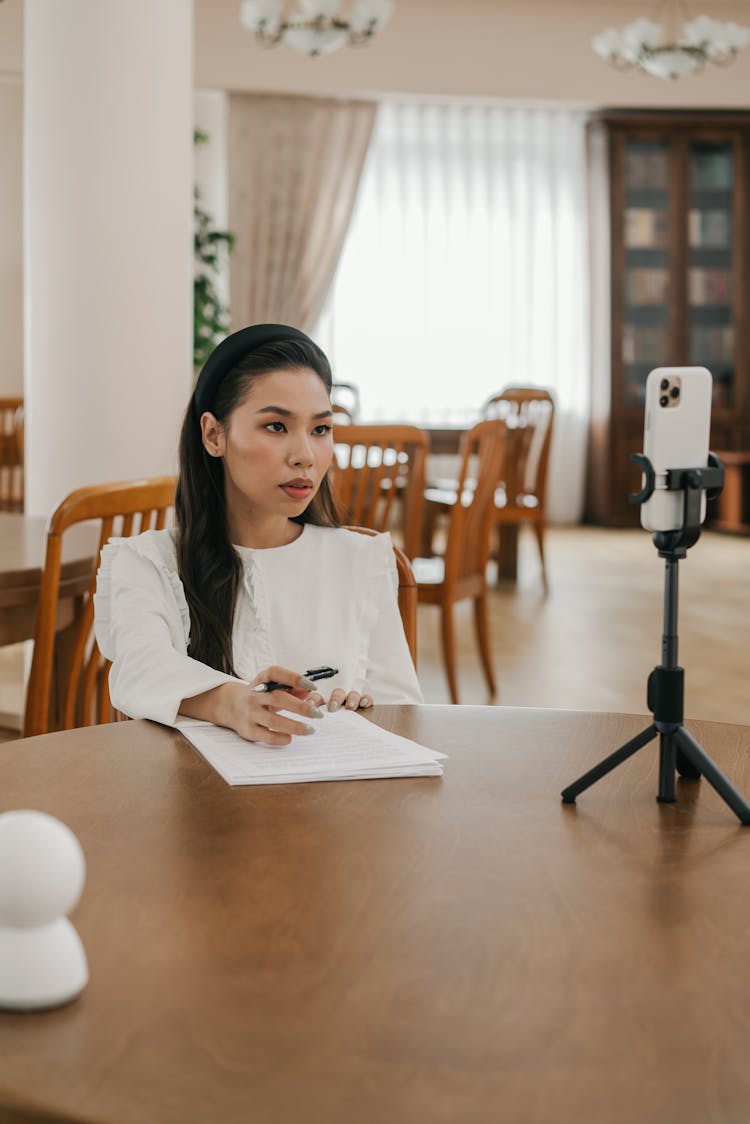 Woman Looking At Smartphone Screen During Online Meeting