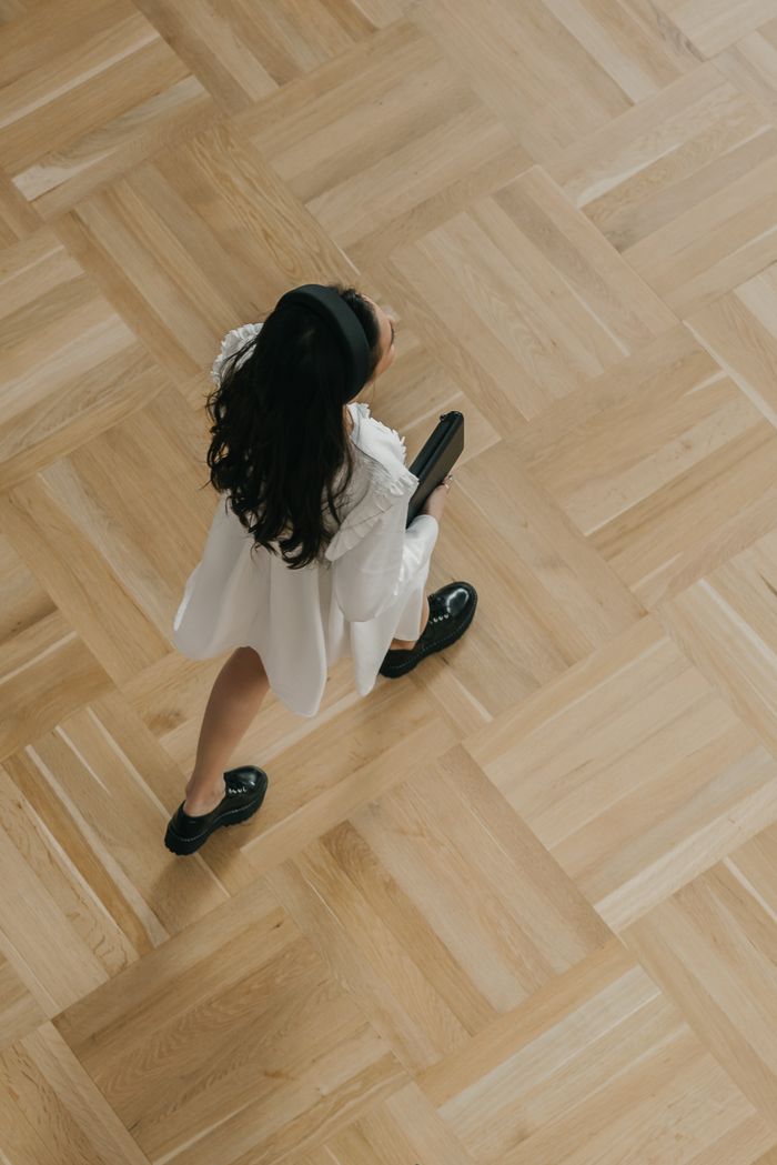Overhead view of a colleague walking across a wooden floor. Photo by Mikhail Nilov on Pexels.