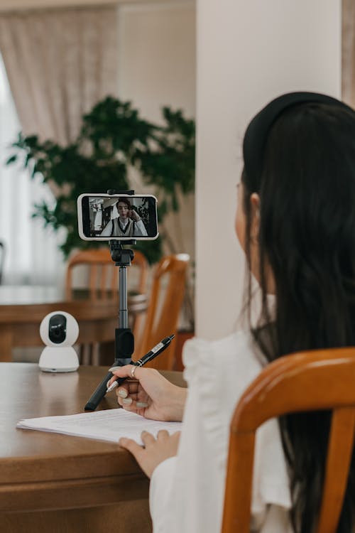 Free A Person on a Video Call Sitting at a Table with a CCTV Unit Stock Photo