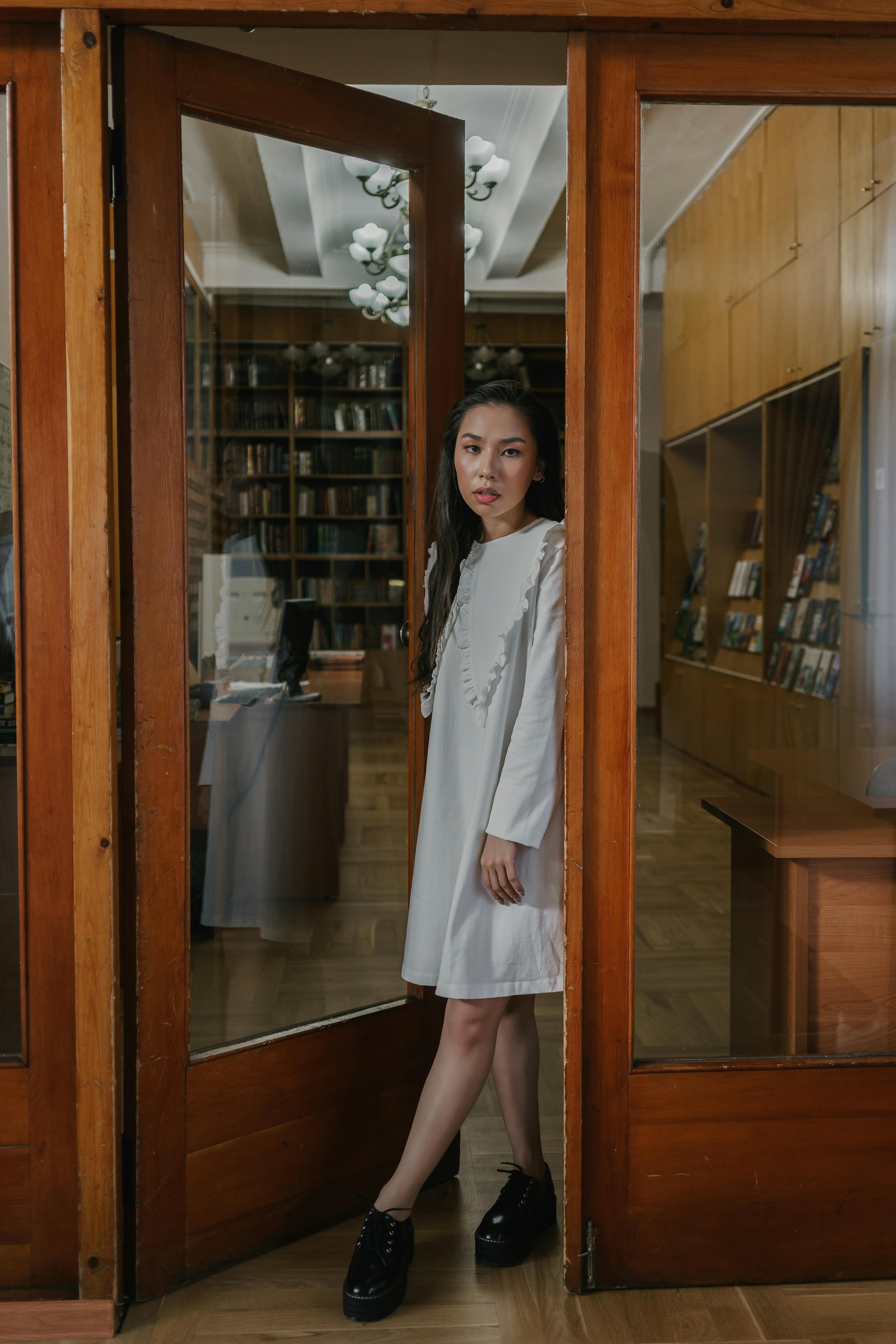 时尚女性站在图书馆门口，结合优雅和现代风格