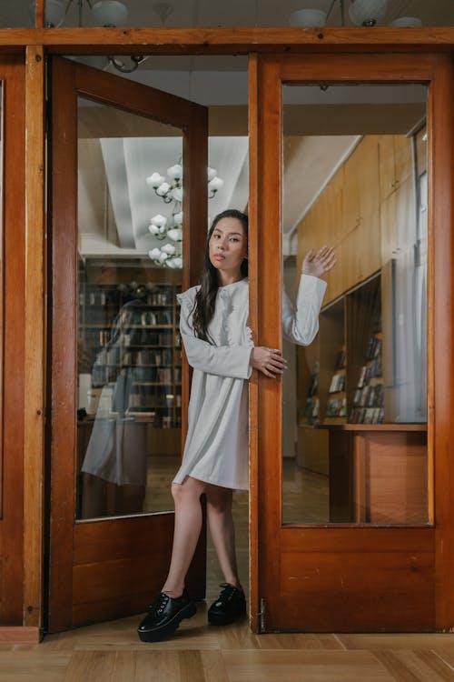 A Woman in White Dress Standing Near in the Doorway
