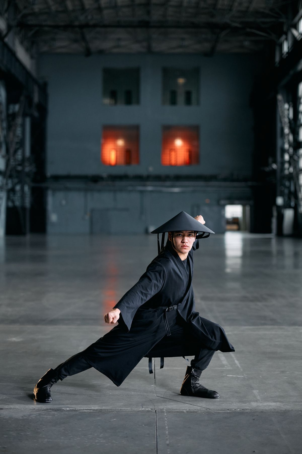 Man in a kung fu stance wearing a conical hat