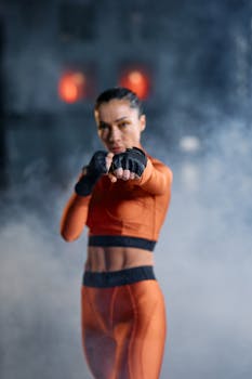 A woman in activewear delivering a punch in a hazy gym scene, demonstrating fitness and strength.