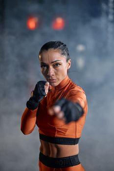 Woman in orange activewear boxing indoors. Fit and determined.
