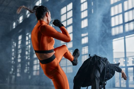 Intense action shot of martial artists engaging in combat within an industrial indoor setting.