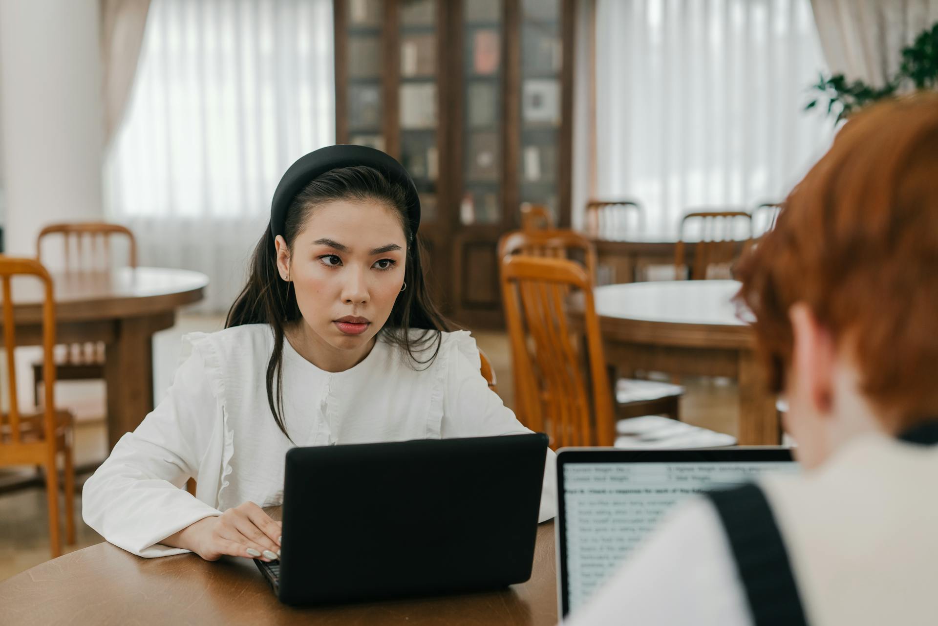 Young woman intensely studying with a laptop in a library setting.