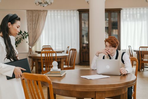 Free Two students engaged in study at a library with laptops and books. Stock Photo