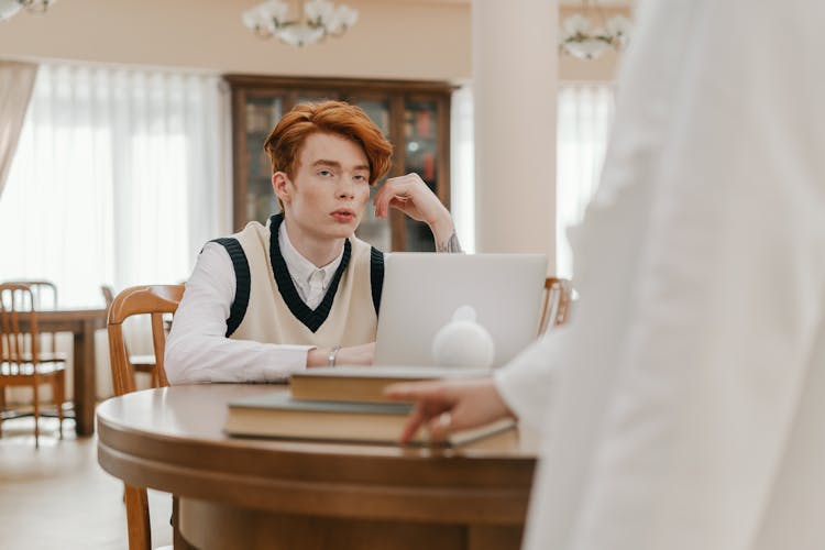 A Man In White Long Sleeves Sitting Near The Wooden Table