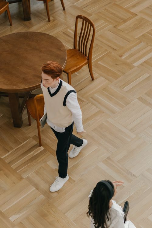 Free Students walking inside a wooden-floored classroom with chairs and table from a high angle. Stock Photo