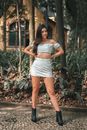Woman in White Lace Crop Top and White Skirt Standing on Brown Leaves