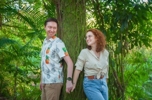 Photo of a Couple Holding Hands Near Green Plants