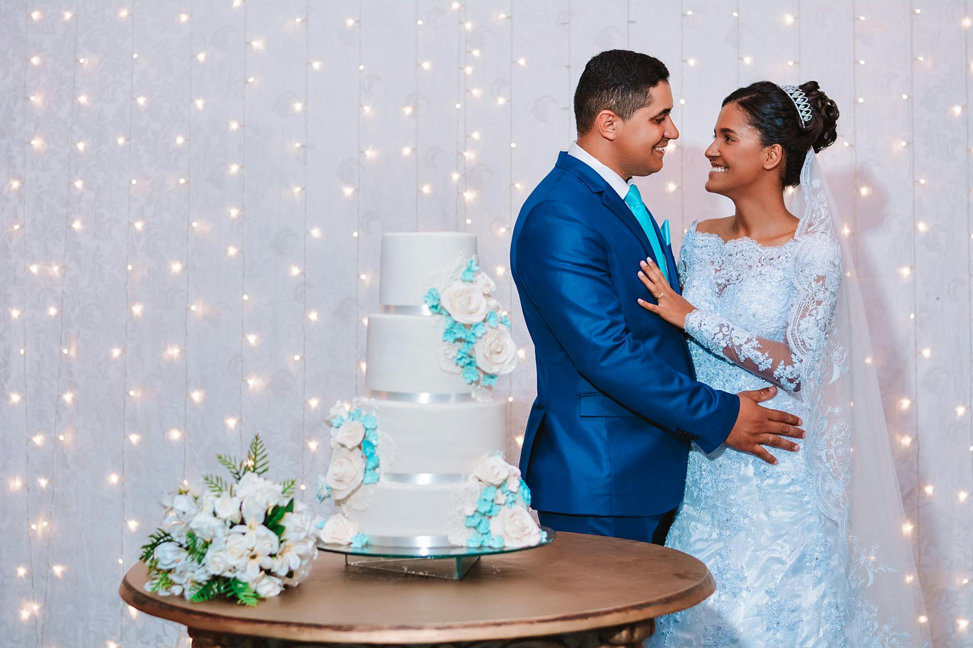 A joyful couple celebrating their wedding with a beautiful tiered cake indoors.