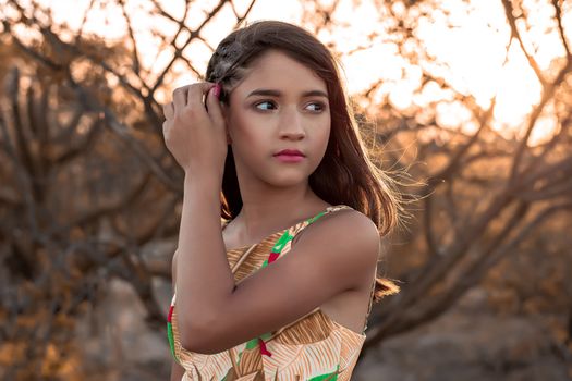 Serene portrait of a young woman outdoors at sunset with soft background.