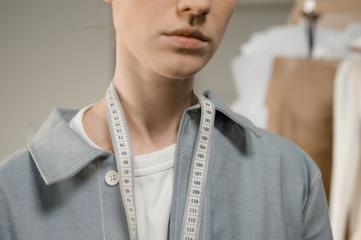 A fashion designer in a studio with a measuring tape draped around the neck, showcasing precision and creativity.