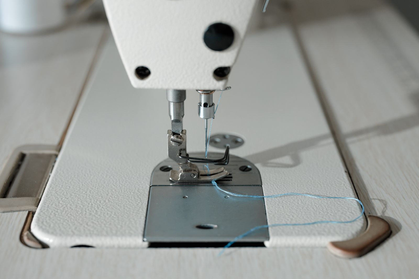 Machine à coudre électronique posée sur table en bois clair, fil et tissu en cours