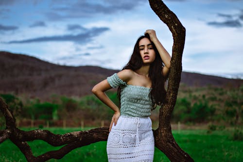 Woman in a Green Off-Shoulder Top Posing Beside a Tree