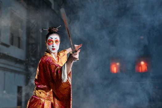 A woman in geisha makeup and traditional kimono poses with a sword amidst dramatic smoke effects.