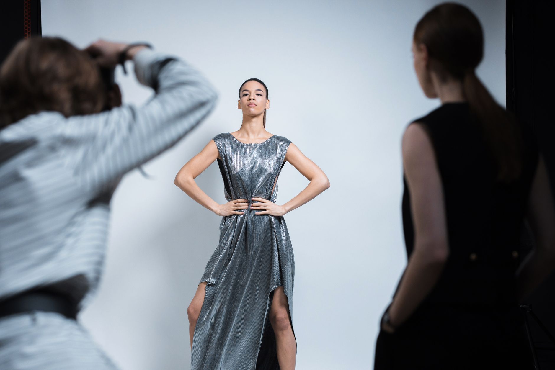 Model posing in a stylish dress during a professional studio photoshoot.