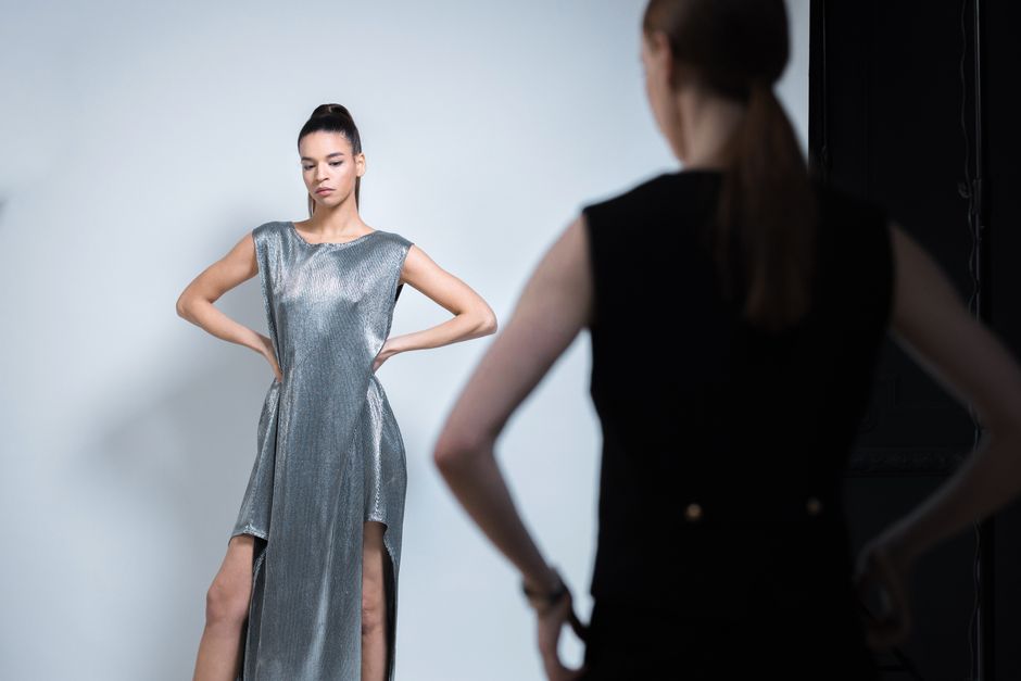 Elegant woman posing in a sleek silver dress during a studio fashion photoshoot.
