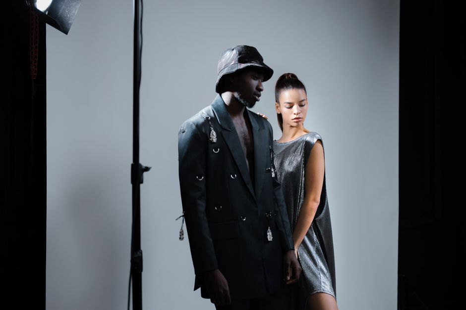 A diverse fashion photoshoot featuring models in a studio with dramatic lighting.
