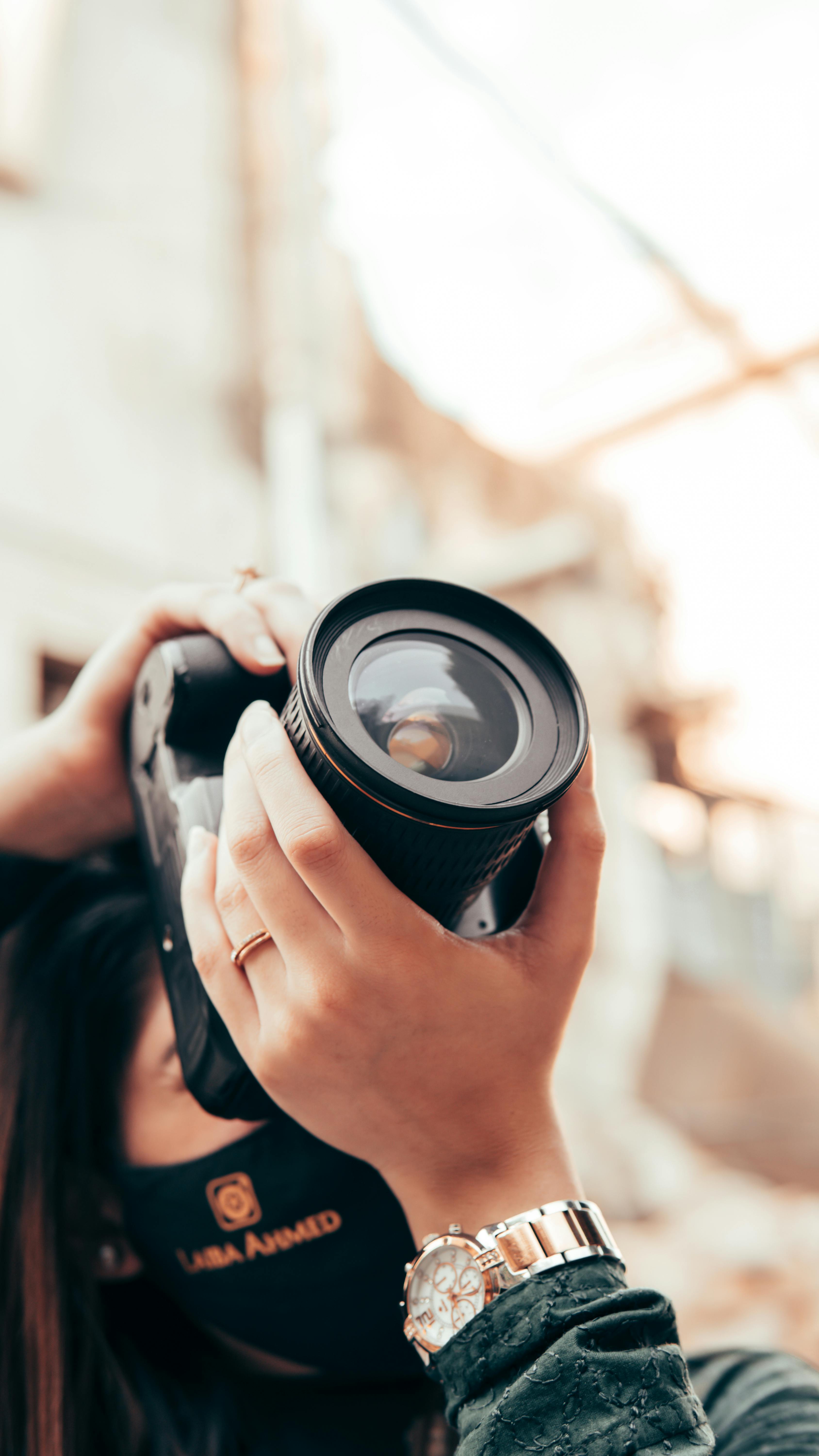 A female photographer in Sialkot, Pakistan, using a DSLR camera to capture urban architecture.