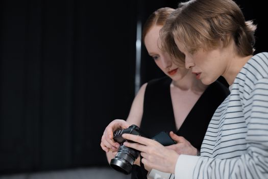 Two women examining a camera indoors with focused attention.