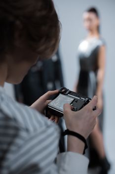 Woman holds a camera while focusing on a photo shoot indoors.