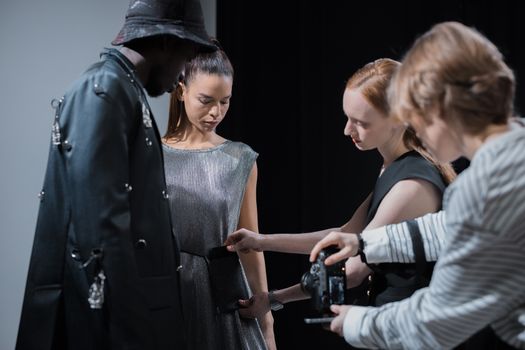 Elegant fashion shoot with models and designer in studio setting.