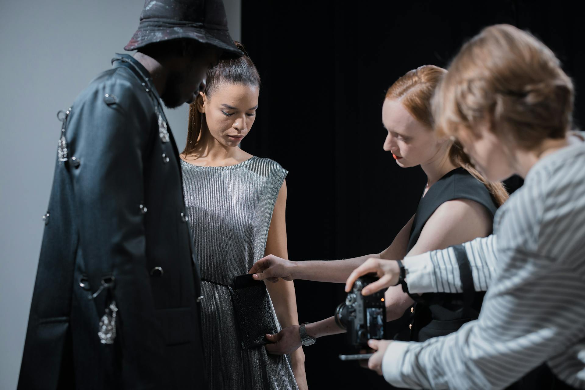 Elegant fashion shoot with models and designer in studio setting.