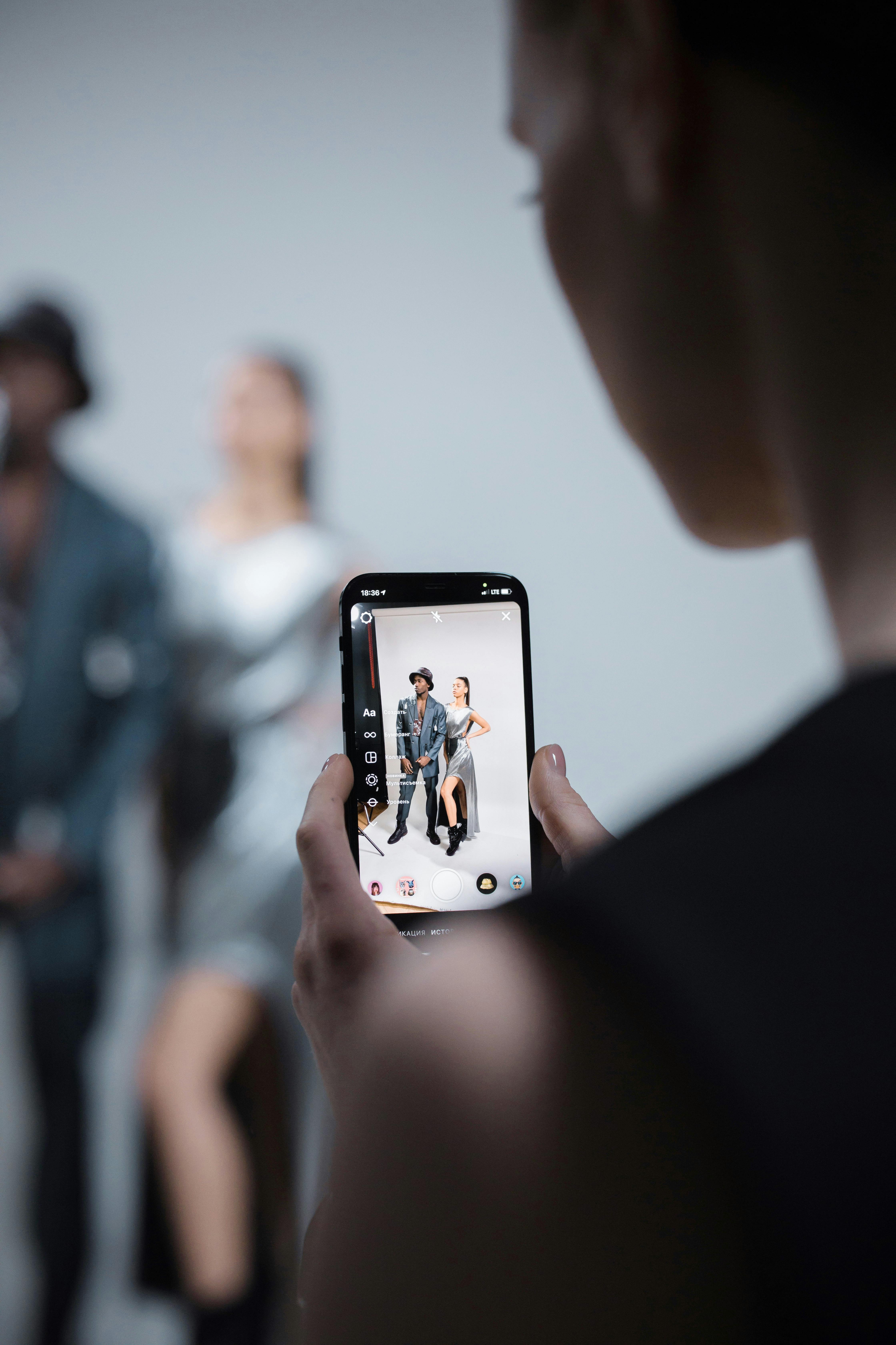 selective focus of a person taking photo of a man and woman