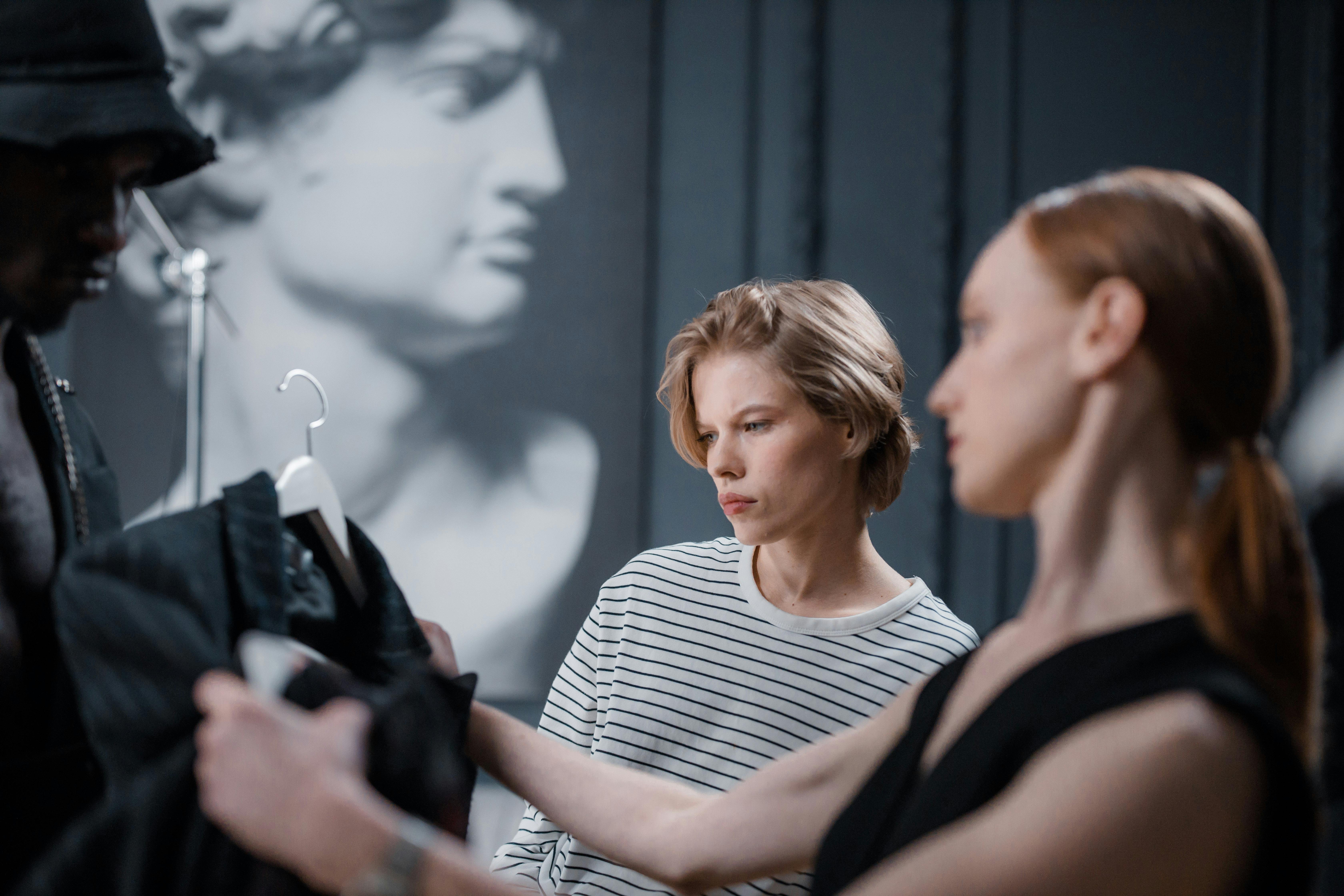 Fashion designers collaborate while reviewing a garment in a modern studio setting.