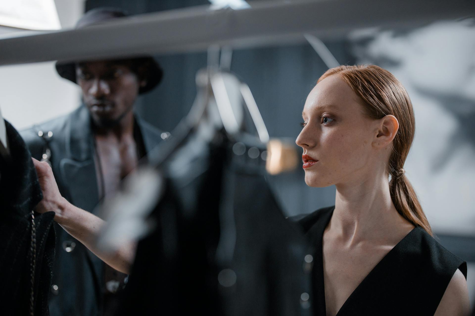 Two fashion designers reviewing clothing in an indoor studio setting, reflecting elegance and style.