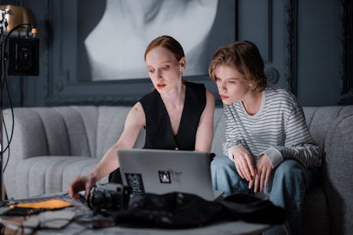 Free Selective Focus of Two Women Sitting on the Couch in Front of a Laptop Stock Photo