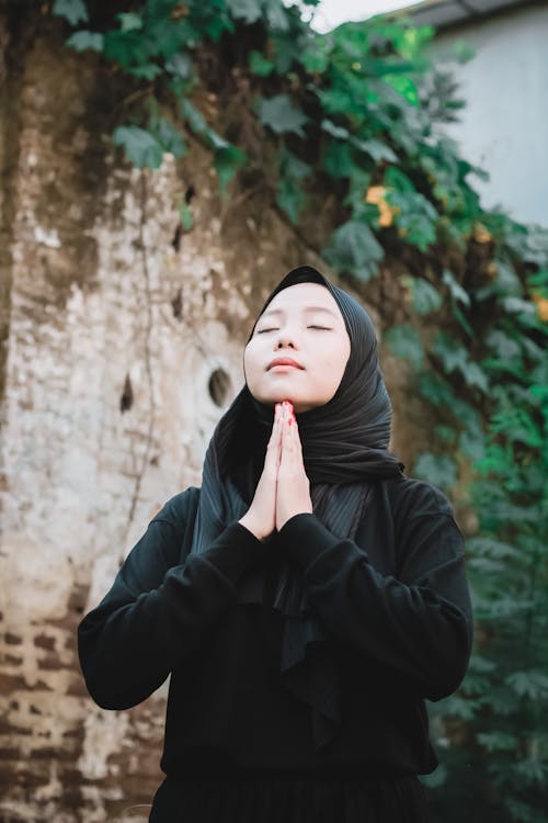 A Woman in Black Hijab Praying