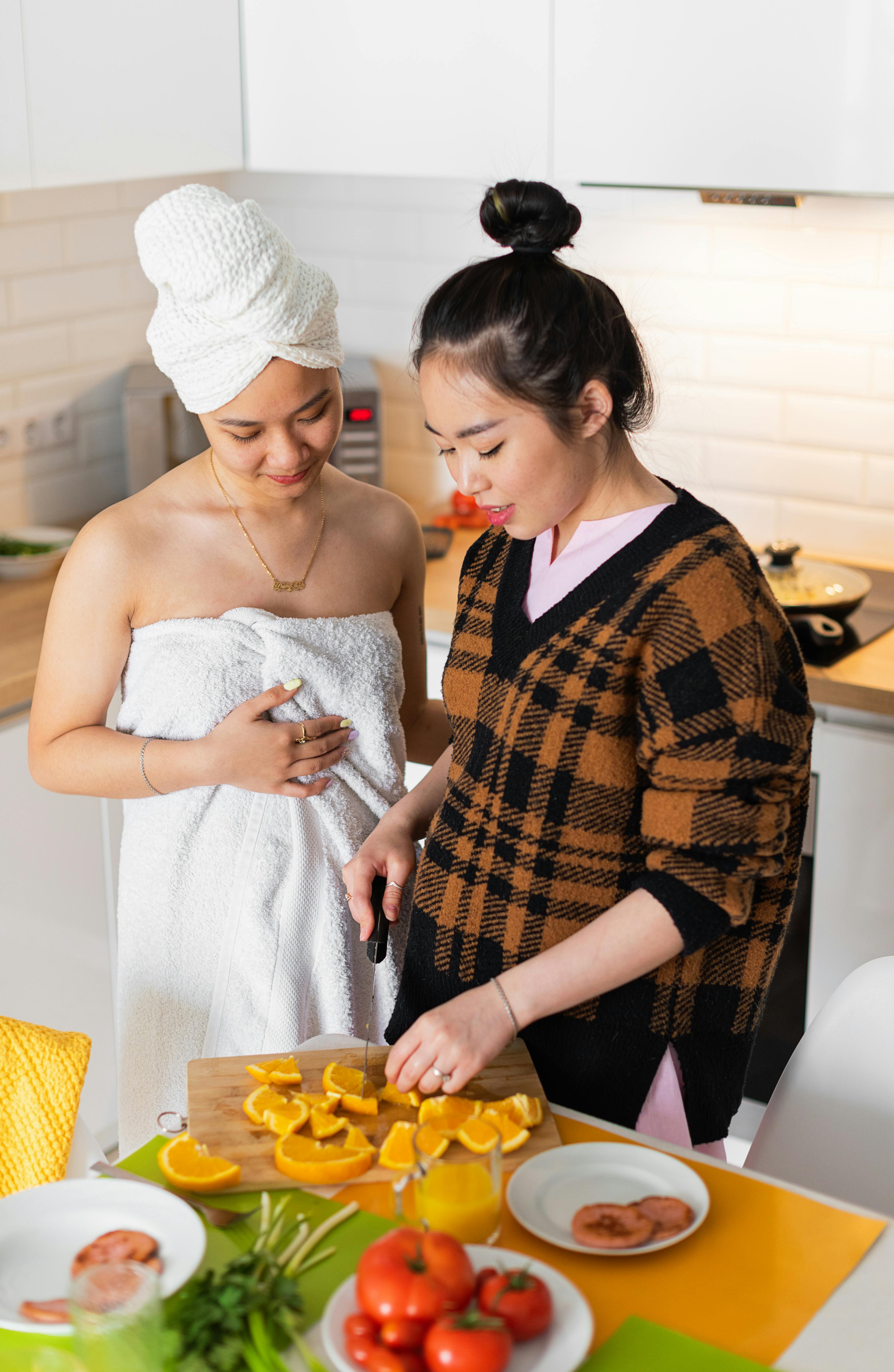 high angle shot of a couple in the kitchen chopping orange fruit