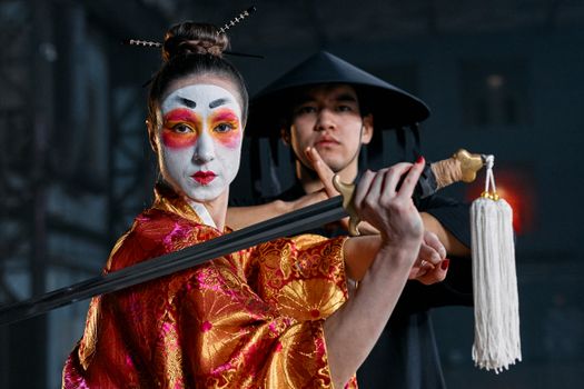 Captivating image of a geisha and ninja in traditional costumes, showcasing dramatic pose and makeup.