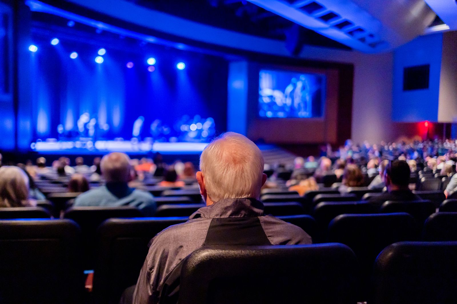An audience seated in a theater watching a live program on stage