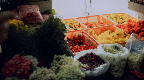 Free Market stall filled with baskets and plastic bags full of bright colorful flowers and grass for sale in daytime Stock Photo