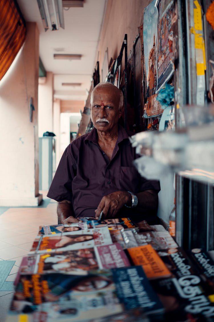 Senior Indian Man Sitting Near Showcase