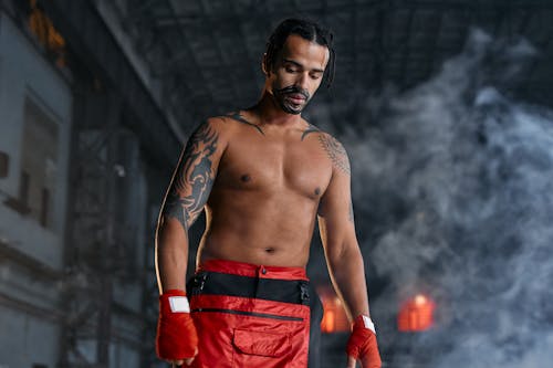 Free A Shirtless Man With Tattoos Wearing Red Gloves Stock Photo