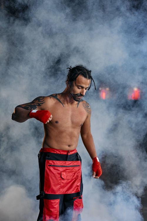 Free A Shirtless Man With Clenched Fist Near Smoke Stock Photo