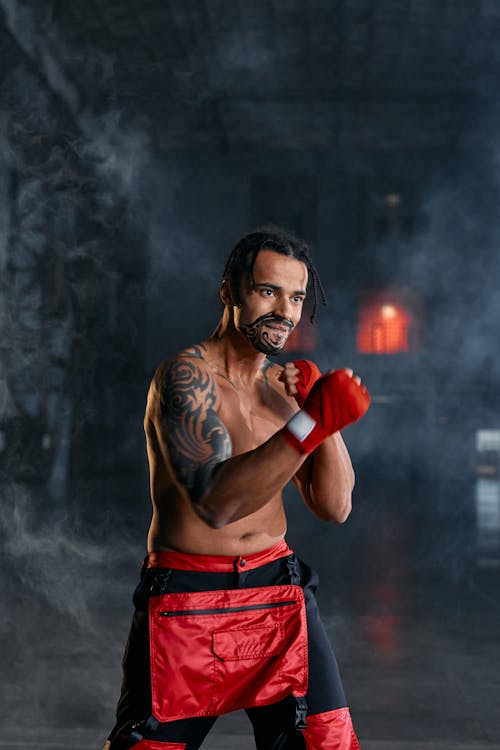 Free A Shirtless Man With Arm and Facial Tattoo With Red Gloves Stock Photo