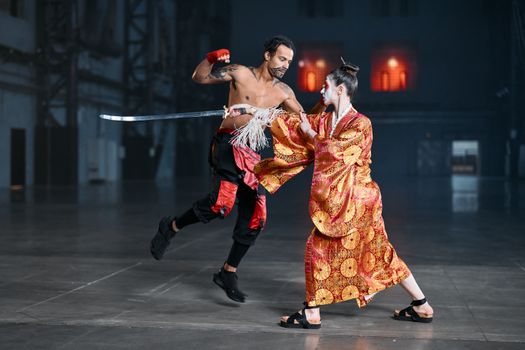 A dynamic martial arts cosplay scene featuring a kimono-clad fighter and a tattooed fighter in motion, indoors.