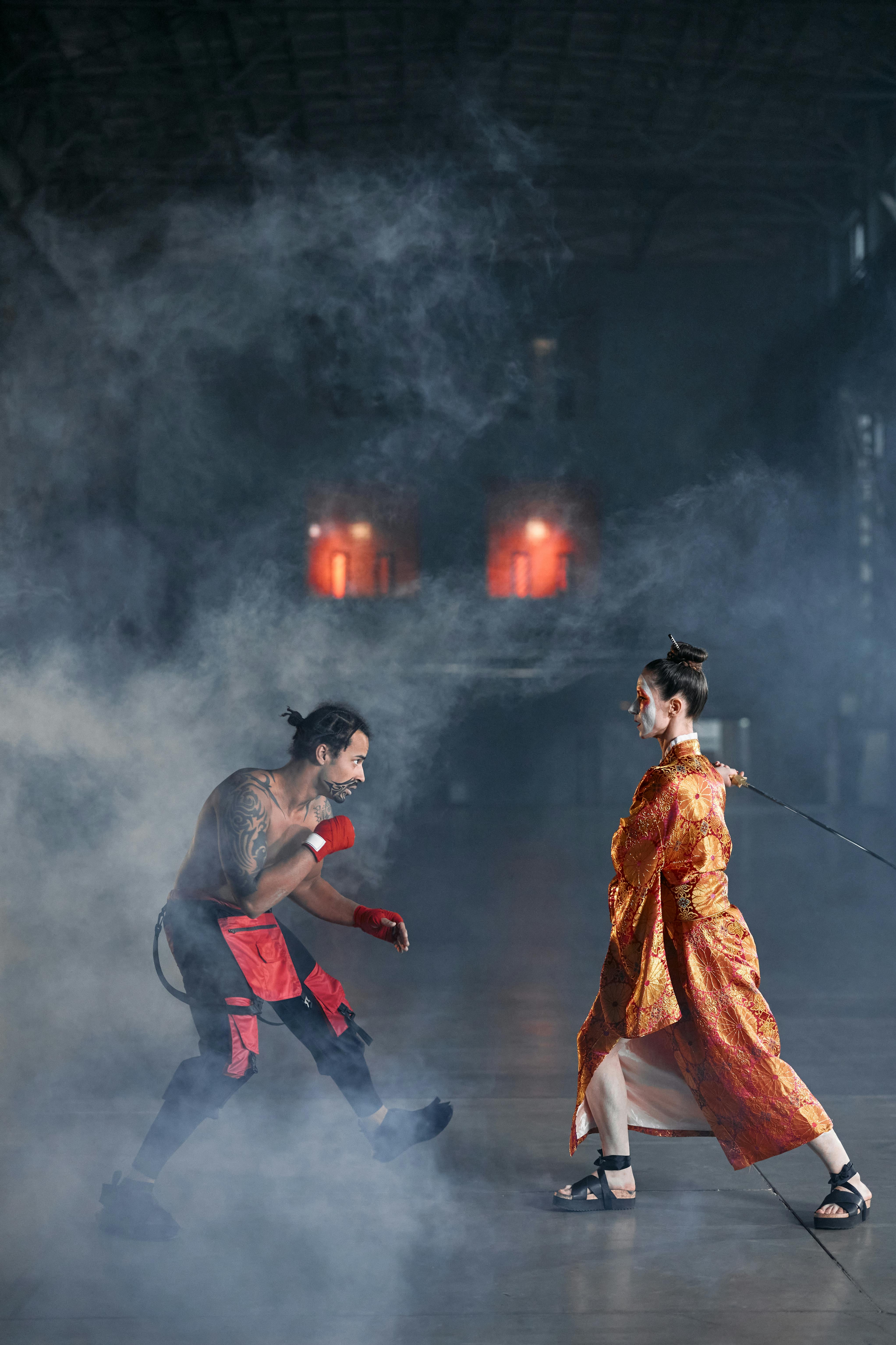 Free Intense cosplay fight scene with dramatic smoke and costumes in a dimly lit setting. Stock Photo